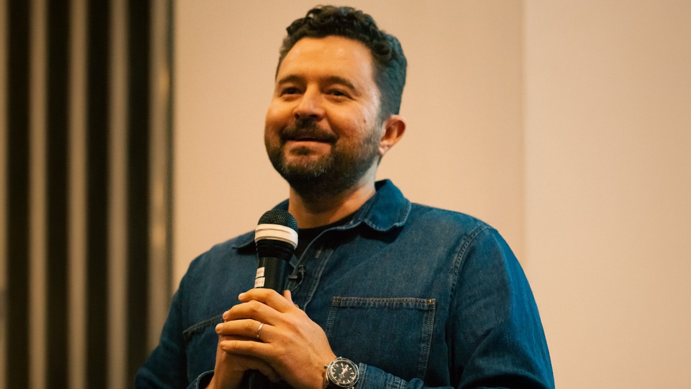 an a white male entrepreneur with brown hair in a Demin shirt speaking at a live event